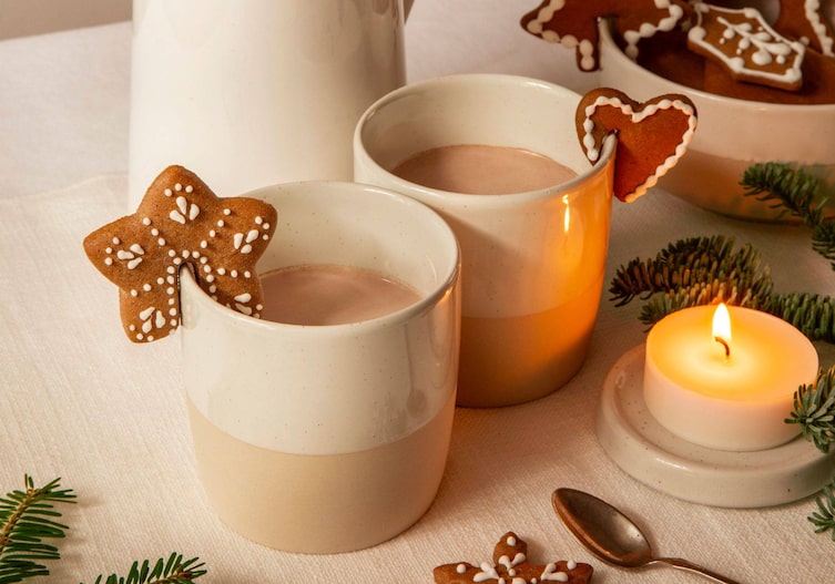 Gefüllte Kakaohäferl ohne Henkel, auf die Häferl sind Lebkuchenkekse gesteckt.