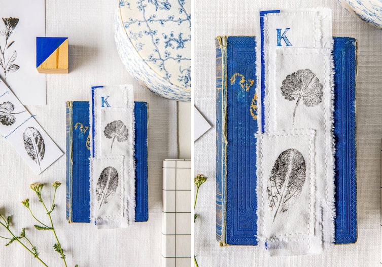 Blaues Buch auf einer weißen Unterlage, auf dem Buch liegt ein länglich genähtes Stofflesezeichen mit Blätterdruck.