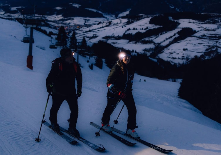 Conny Bürgler und Gerhard Ottino mit Tourenski auf Piste in der Dunkelheit