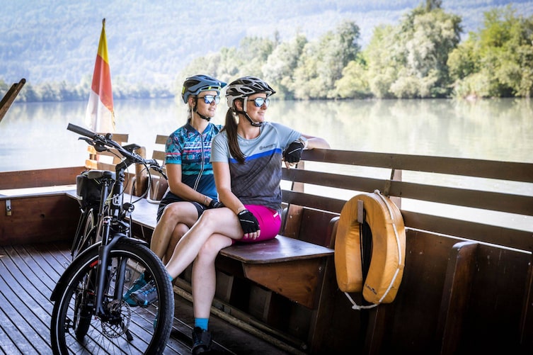 Zwei Radlerinnen genießen die Überfahrt mit der Fähre in Österreich.