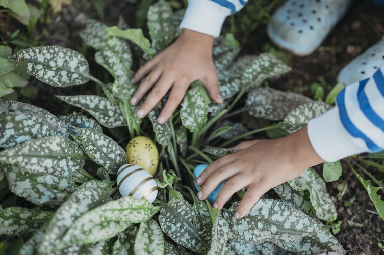 Kinderhände die Ostereier in einem Strauch finden