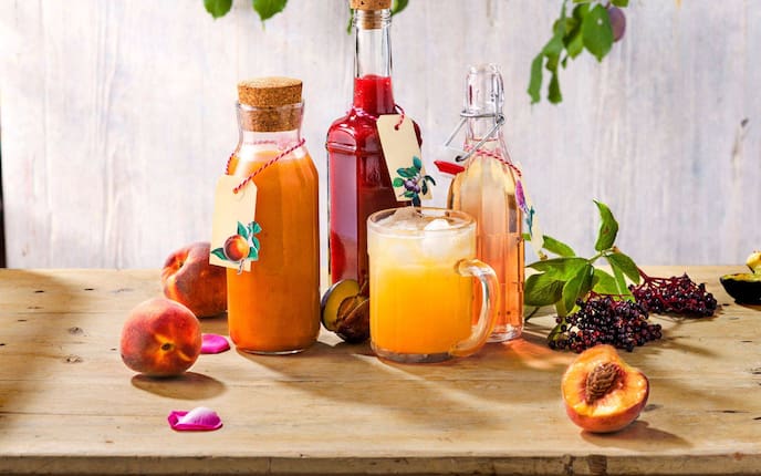 Pfirsichsirup, Hollerbeerensirup, Fliedersirup in Flaschen.