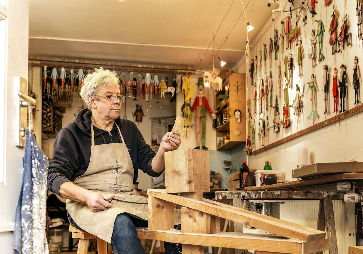 Markus Wagner sitzt auf der Schnitzbank und beäugt das dünne Stück Holz, das er soeben von einem Bergfichtenblock gespalten hat. Es wird der Korpus eines Hasen.