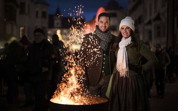 Richie Deutinger und Conny Bürgler stehen bei einer Feuerschale am TIroler Weihnachtsmarkt.