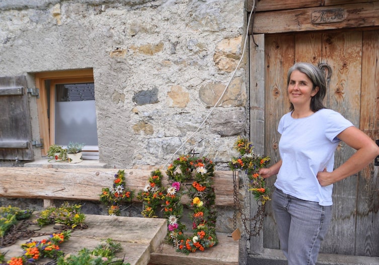 Petra Rinderer posiert für ein Foto mit den fertigen Blumengestecken für den Alpenabtrieb der Hutla-Alpe