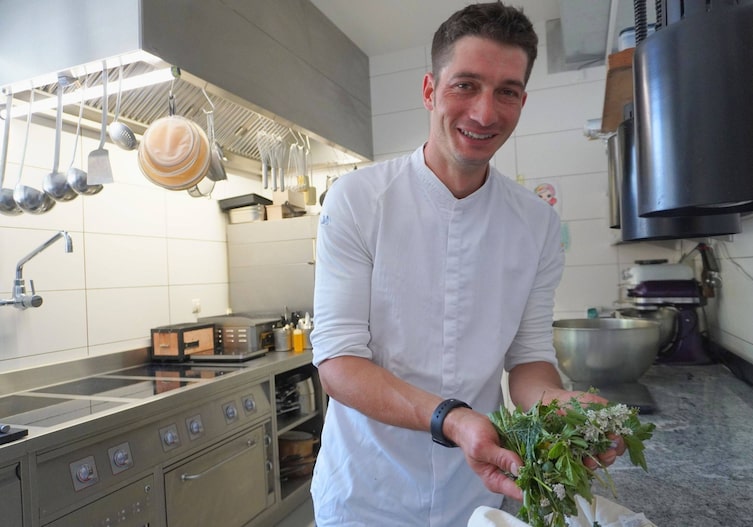 Tobias Schöpf posiert für ein Foto mit gesammelten Kräutern in seiner Küche