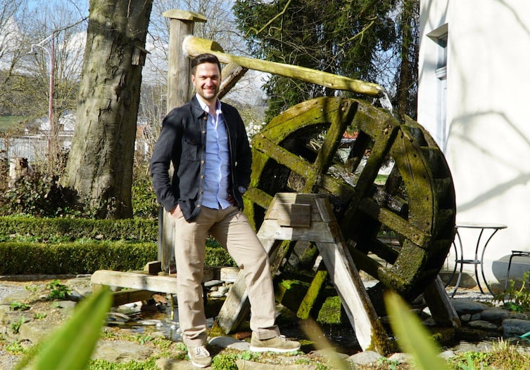 Richard Deutinger steht vor einem alten Wasserrad in der Berghofer Mühle