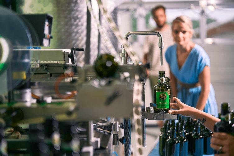 Eine moderne Maschine füllt das Kürbiskernöl in die Flaschen mit grünem Etikett ab.