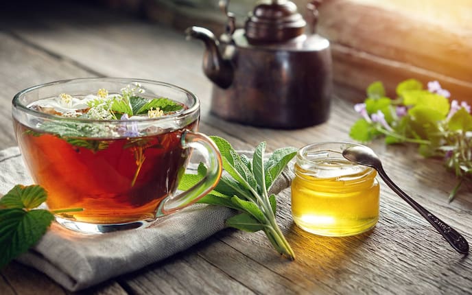 Kräutertee, Honig, Teetasse, Salbei, Minze, Melissenblätter und Kräuterblüten