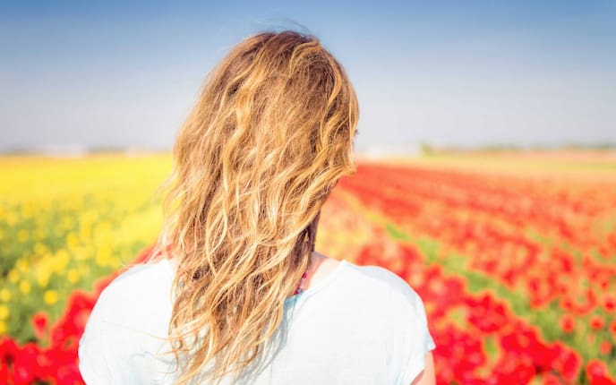 Blonde Frau schaut auf blühendes Mohnfeld. (Bild: Getty Images)