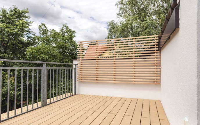 Terrasse mit Holzboden und Rankgerüst.