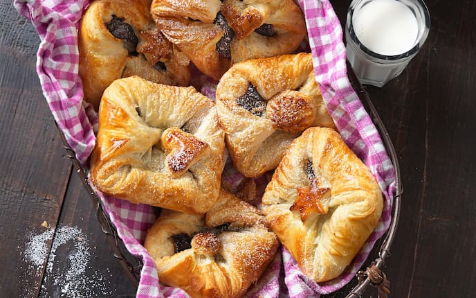 Powidlgolatschen, Germteig, Milch, Staubzucker, Küchentuch, Körbchen, Holztisch