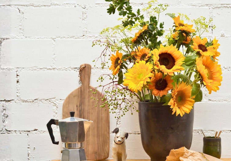 Braune Vase mit verschiedenen Sonnenblumen und Holler