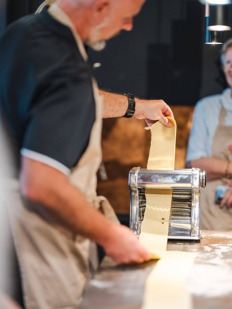 Teig wird durch eine Nudelteigwalze gerollt.