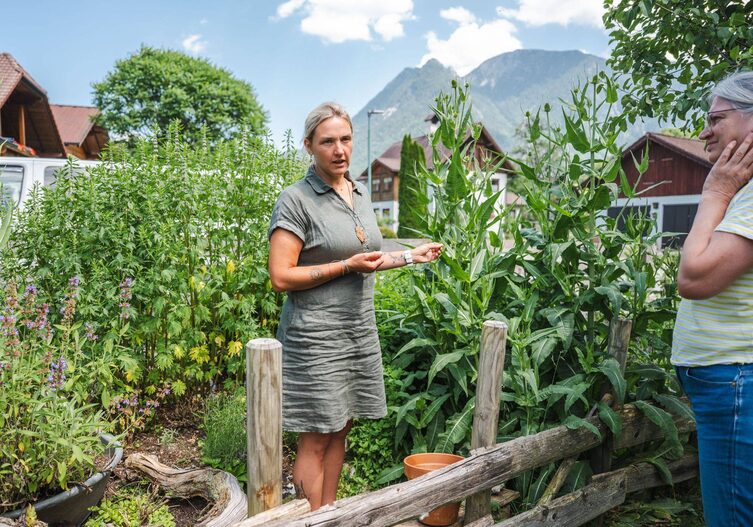 Tanja steht in ihrem Kräutergarten. Im Hintergrund sieht man Berge.