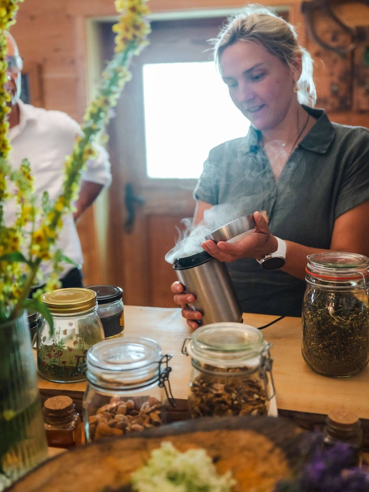 Tanja öffnet eine Mahlmaschine und es kommt eine Rauchwolke von Kräutern heraus.