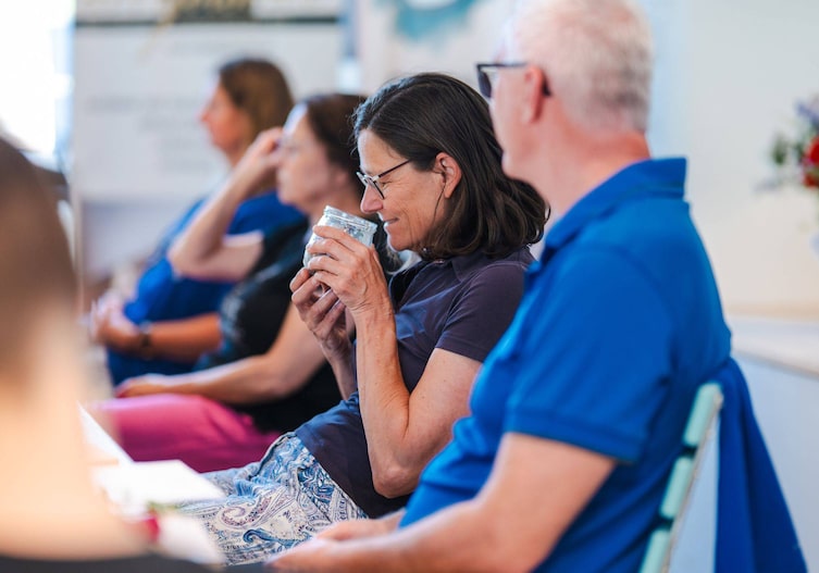 Eine Frau riecht an einem Glas.