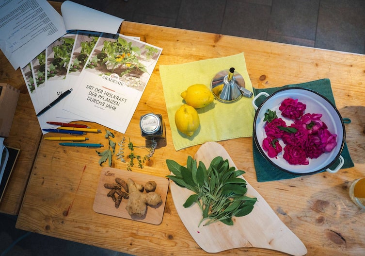 Ein Tisch mit diversen Zutaten, Malven, Salbei, Ingwer, Kurkuma und Zitronen.