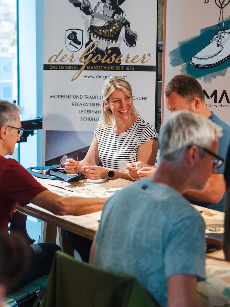 Eine lachende Frau, die sich ihren eigenen Schuh näht.