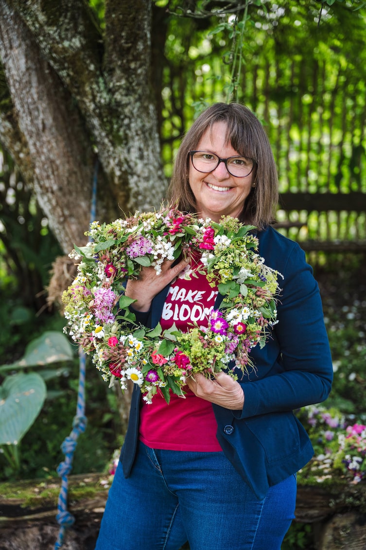 Die Teilnehmerin präsentiert stolz ihren fertig gebunden Blumenkranz.