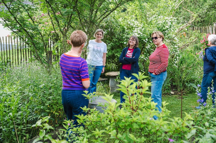 Irmgard Gamsjäger führt die Gruppe durch ihre Naturwerkstätte, ihren blühenden Garten, und zeigt verschiedene Pflanzen und Materialien.