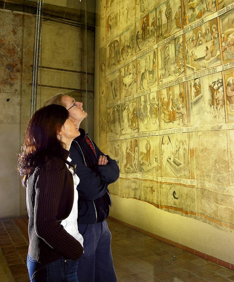 Eine Frau und ein Mann erkunden das große Fastentuch Zittaus.