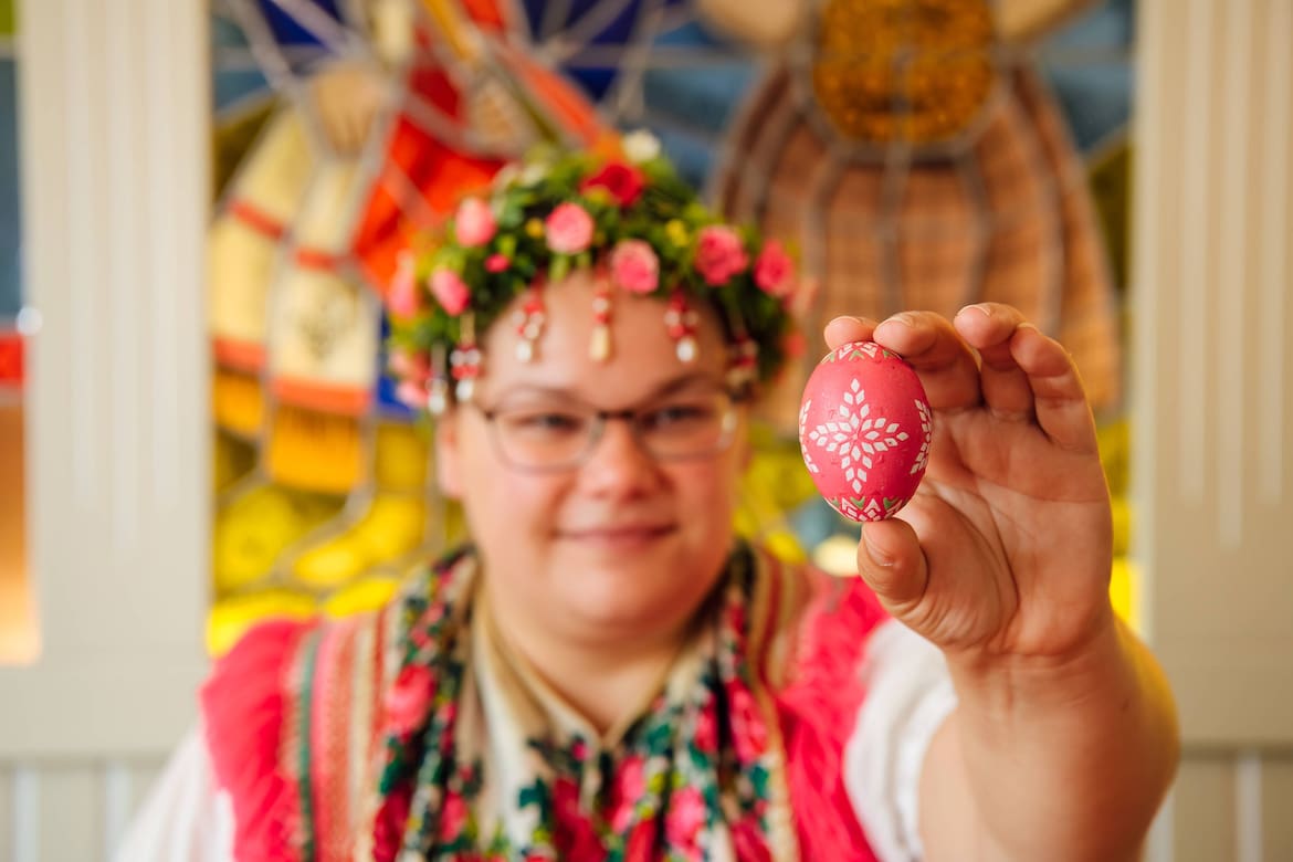 Eine Frau hält ein verziertes Osterei in der Hand.