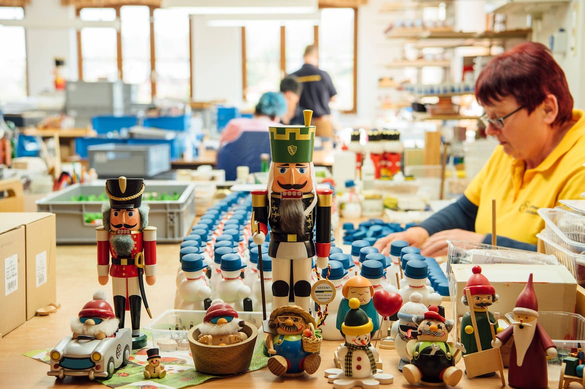 Eine Dame sortiert die kleinen Nussknacker aus Holz im Museum.