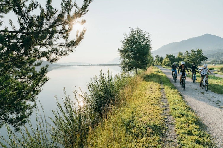 Eine vierköpfige Familie radelt entlang des idyllischen Drauradwegs.