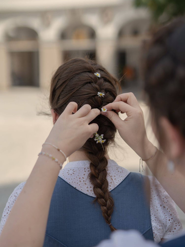 Gänseblümchen werden in den Zopf gesteckt.