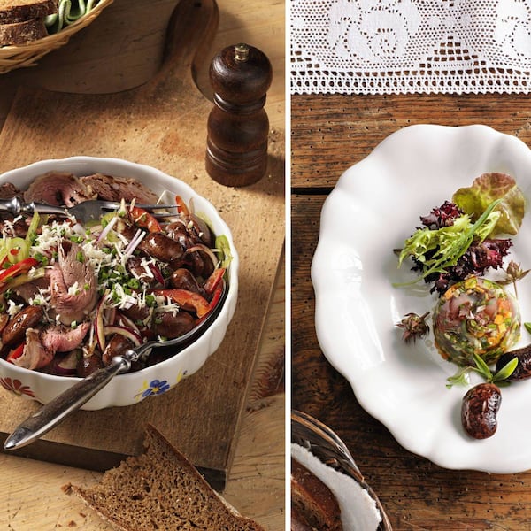 Alt-Text: Zwei steirische Käferbohnen-Gerichte im Vergleich: links Käferbohnensalat mit blättrig geschnittenem Tafelspitz, roten Paprikastreifen, Schnittlauch und frisch geriebenem Kren in einer geblümten Keramikschüssel auf einem Holzbrett; rechts eine elegant angerichtete Käferbohnensulz mit Wurzelgemüse und gemischtem Blattsalat auf weißem Porzellan, garniert mit ganzen Käferbohnen und frischen Kräutern.