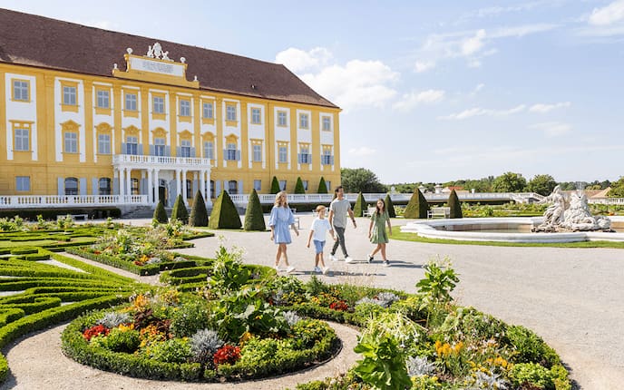 Eine Familie geht zu viert im Schloss Hof herum und sieht sich den Barockgarten an.