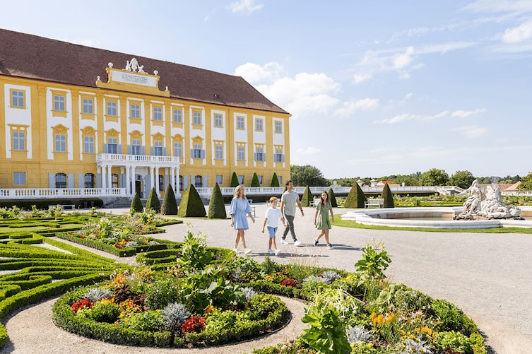 Eine Familie geht zu viert im Schloss Hof herum und sieht sich den Barockgarten an.