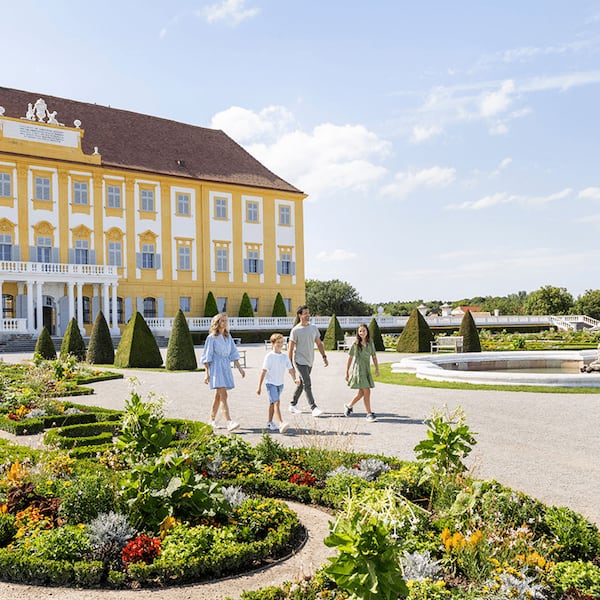 Eine Familie geht zu viert im Schloss Hof herum und sieht sich den Barockgarten an.