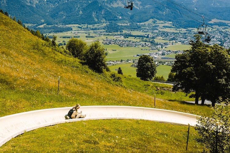 Eine Frau rutscht die Sommerrodelbahn am Hochkönig herunter