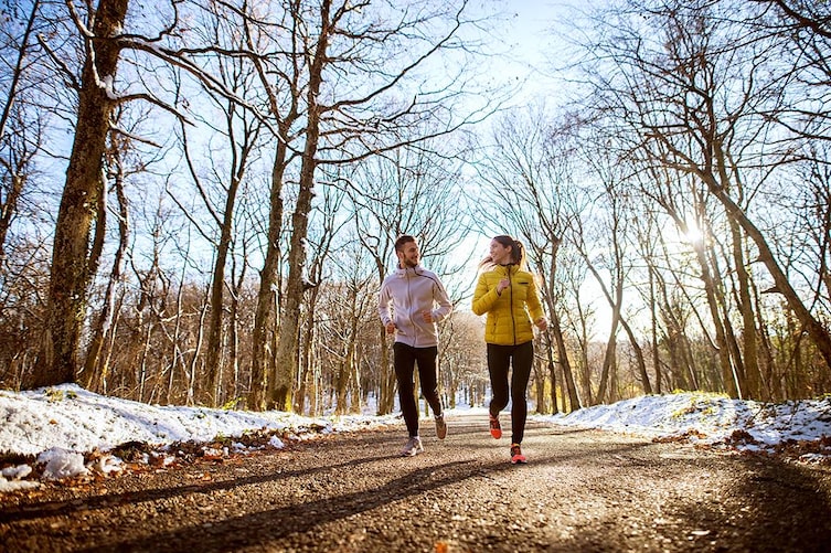 zwei läufer im winterlichen wald bei sonnenschein