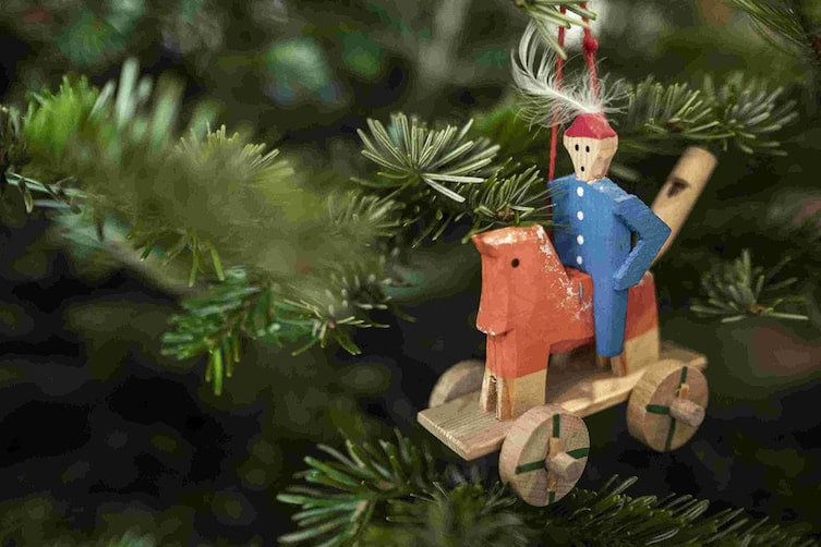 Nahaufnahme einer traditionellen Berchtesgadener Holzfigur als Christbaumschmuck an einem Tannenzweig.