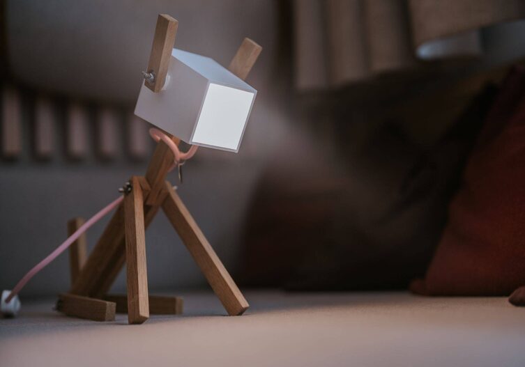 Eine kleine Stehlampe aus Holz, die einen sitzenden Hund imitiert.