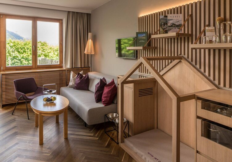 Ein Hotelzimmer mit Sofa, und einer eigenen Ecke für Hunde mit Schlafplatz