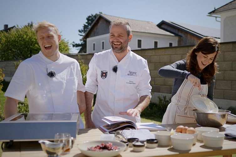 Nationalspieler Xaver Schlager, ÖFB-Koch Fritz Grampelhuber und ServusTV-Reporterin Julia Kienast in der provisorischen Gartenküche beim Dorfwirt in St. Valentin.