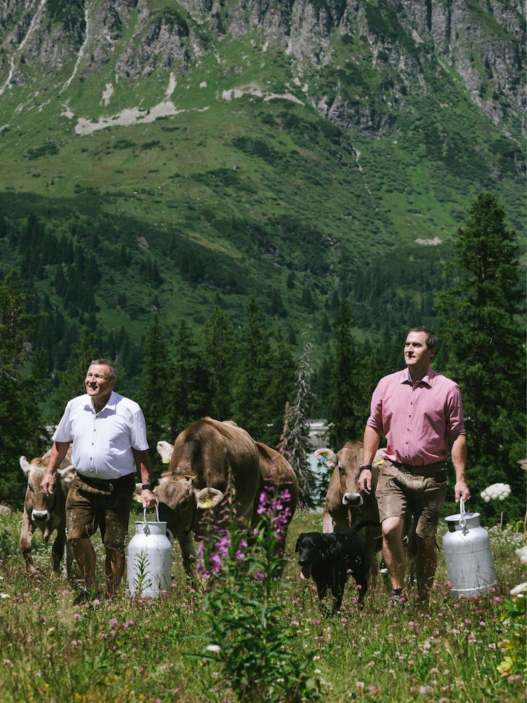 Hermann und sein Sohn Patrick Huber mit Milchkannen bei den Kühen auf der Faulbrunn Alm.