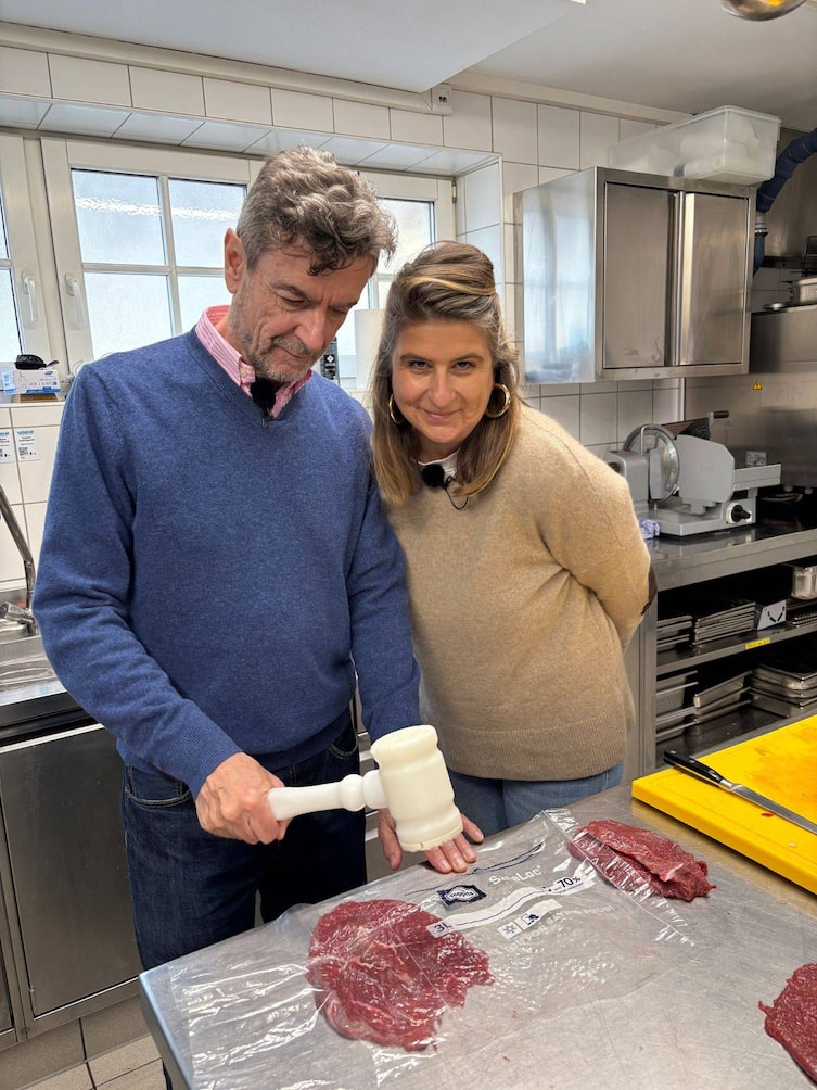 Mesi schaut Harald beim Schnitzelklopfen auf die Finger.
