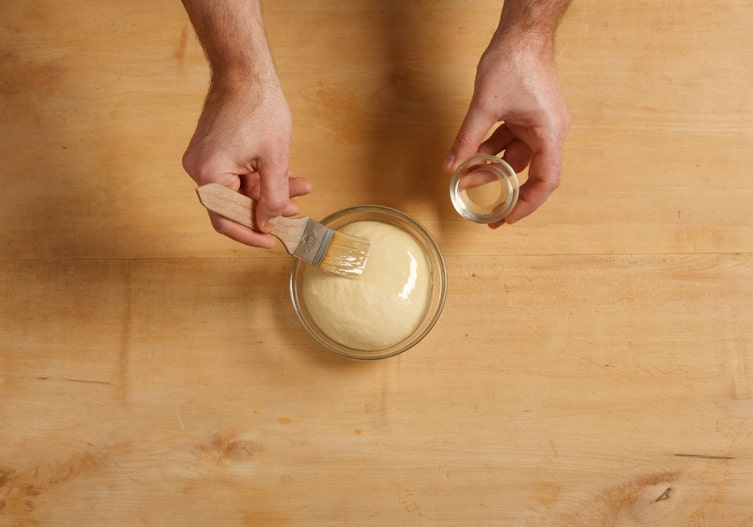 Breitenfurter Millirahmstrudel, Strudelteig, Glasschüssel, Hände, Pinsel, Öl