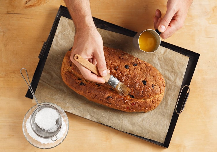 Christstollen, flüssige Butter, Staubzucker, Sieb