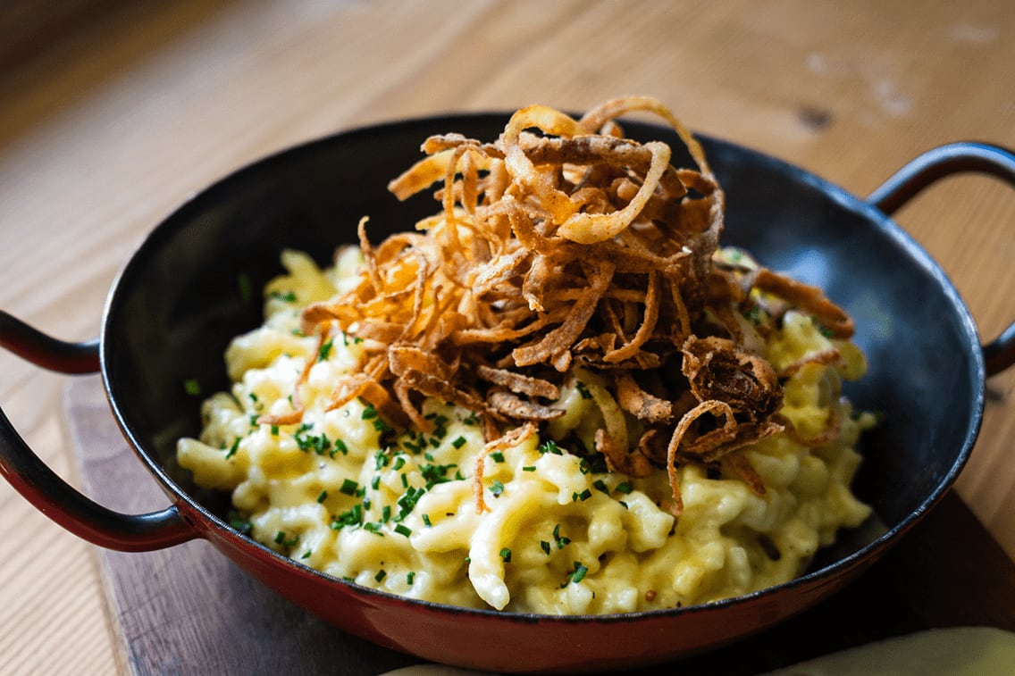 Zu sehen sind Käsespätzle mit knusprigen Röstzwiebeln garniert.