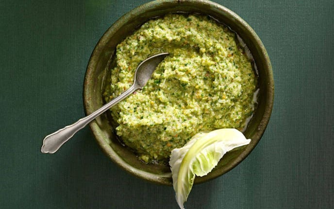 Pesto in einer grüner Keramikschüssel mit einem alten Teelöffel und einem Karfiolblatt