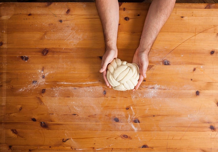Geflochtene Brotkugel, Germteig, Tischplatte, Hände, Mehl