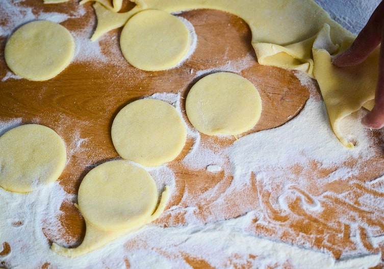 Eine Holzplatte, gut eingemehlt, und ausgestochene runde Teigstücke.