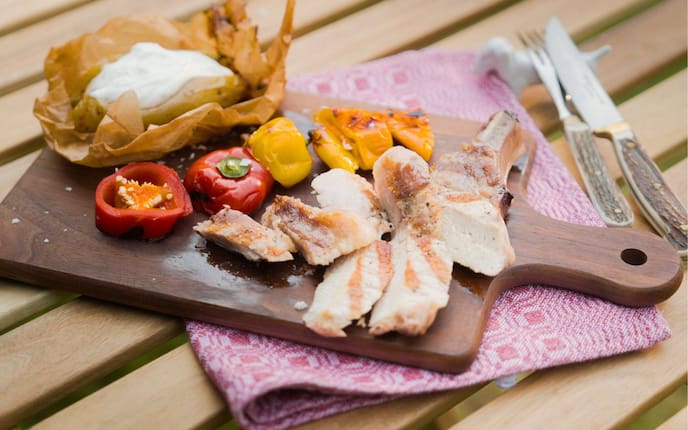 Schweinekotelett vom Grill auf einem Holzbrett mit Erdäpfel