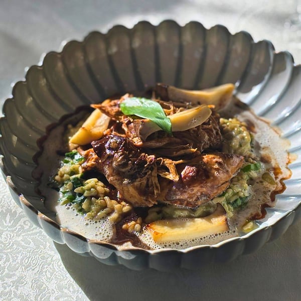 Gezupftes Landhendl mit Bärlauchrisotto auf einem Teller angerichtet.